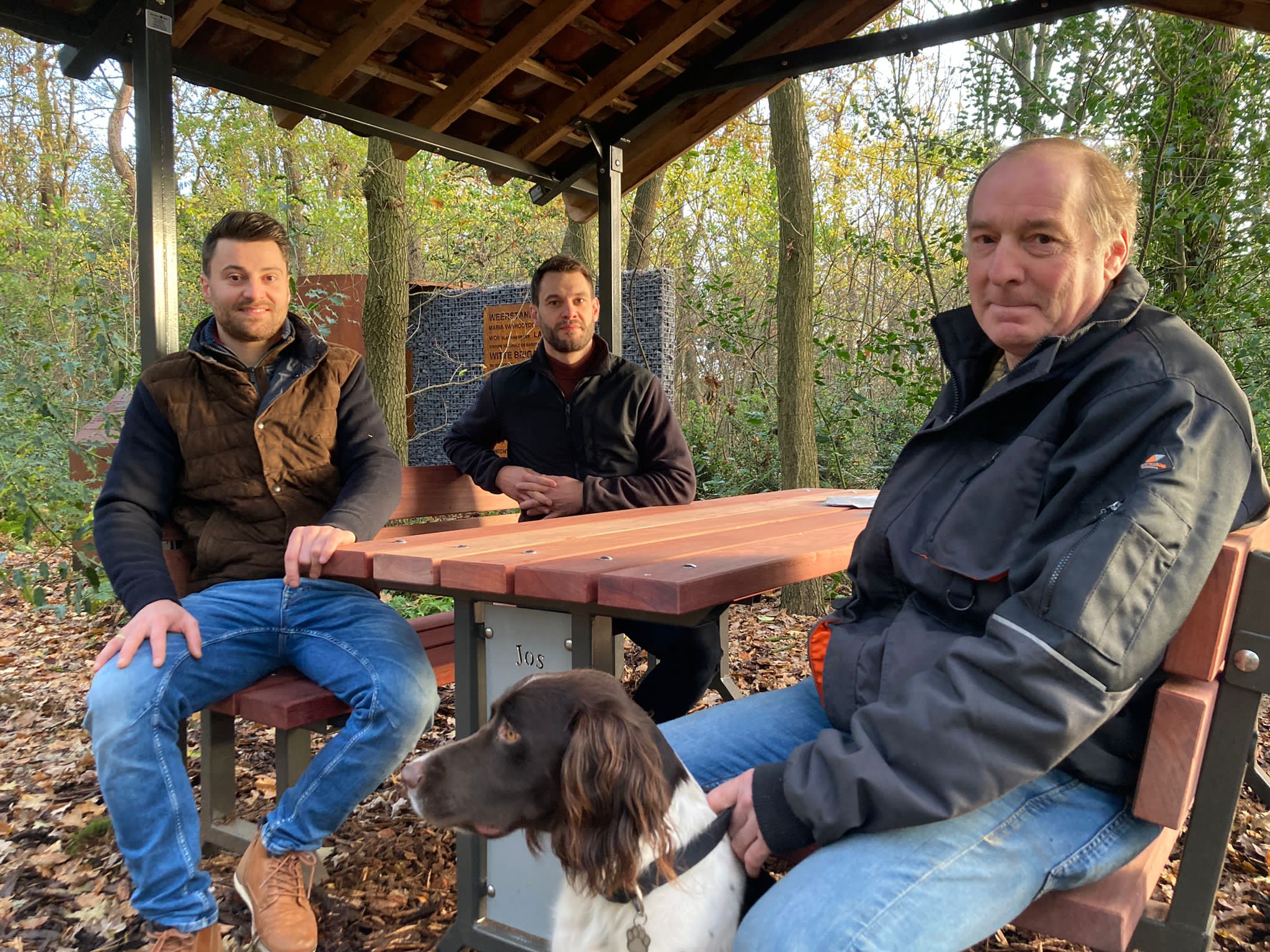 Drie betrokkenen en een hond aan de zitbank van het memorial